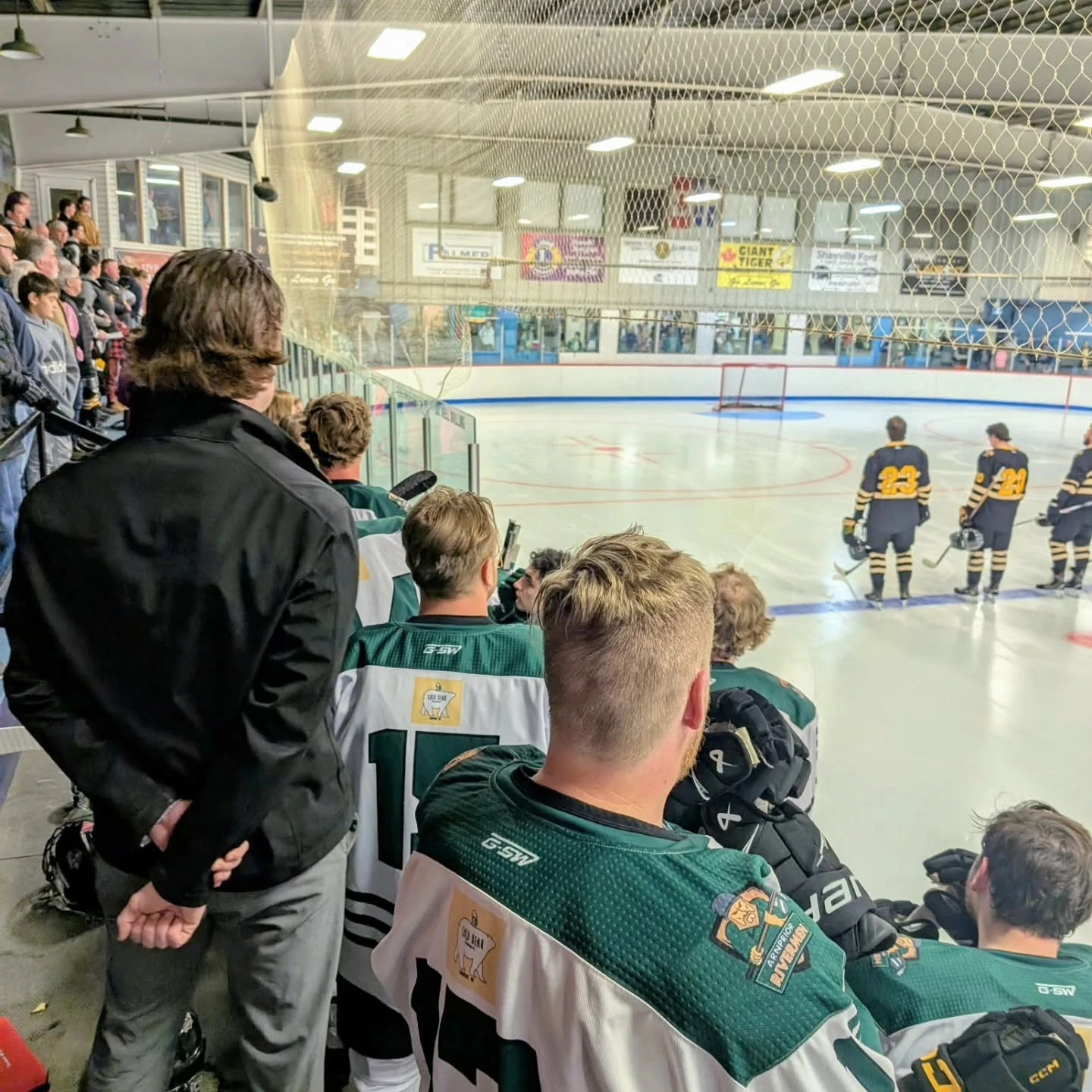 Rivermen players on the bench before puck drop, fans standing behind them